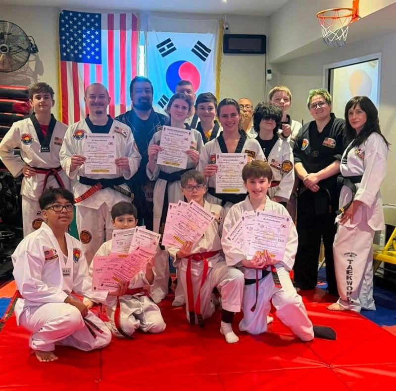 Students celebrating belt promotion test success with certificates